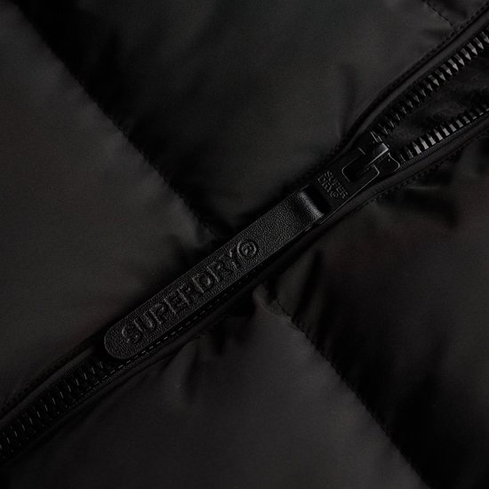 Sluiting van een zwarte Superdry pufferjas, met Superdry-logo op de ritslip.