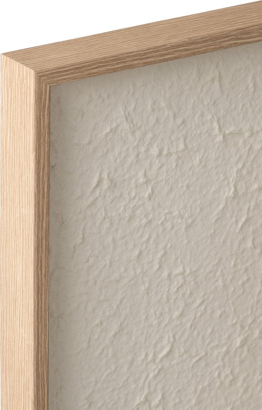 Détail d'un cadre en bois avec une toile texturée brute blanc cassé.