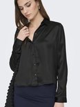 Model draagt een zwarte satijnen blouse met lange mouwen en knopen. Op de rug een kanten rand.