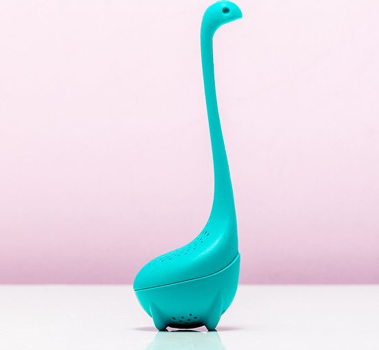 Turquoise dinosaurus-vormige theefilter op een witte ondergrond met zachtroze achtergrond.
