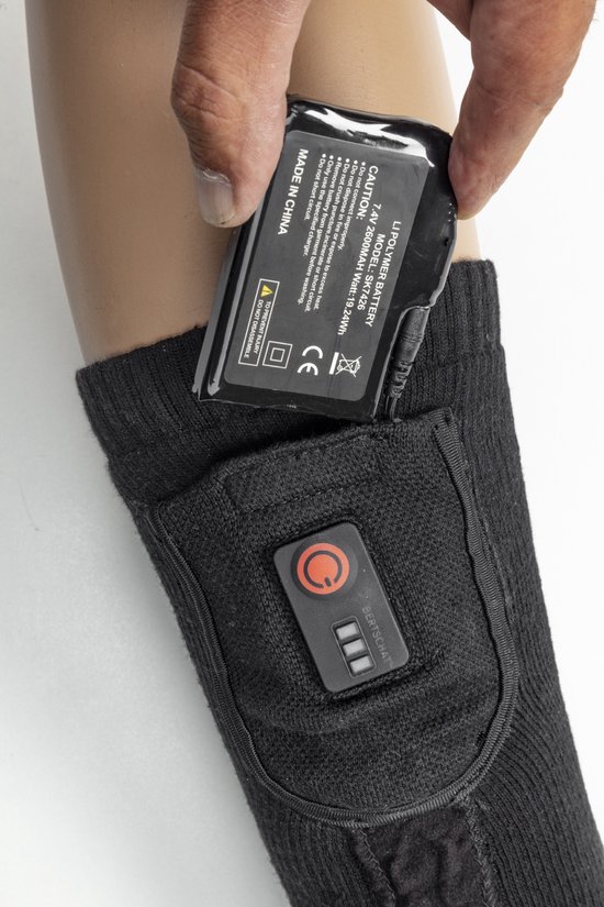 Zwarte verwarmde sok met bedieningspaneel en een hand die een batterij in het vakje plaatst.