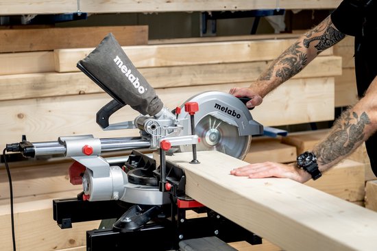 Man met tatoeages zaagt met Metabo afkortzaag.