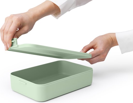 Mains retirant le couvercle d'une boîte à pain Brabantia vert jade.