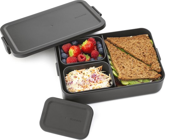 Donkergrijze bento lunchbox met sandwich, fruit, salade, en losse deksels.