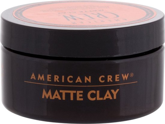 Zwarte pot American Crew Matte Clay met oranje label, op een witte achtergrond.