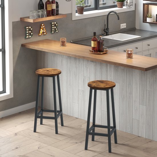 Twee ronde barkrukken met vintage bruine houten zittingen en zwarte metalen frames, naast een bar.