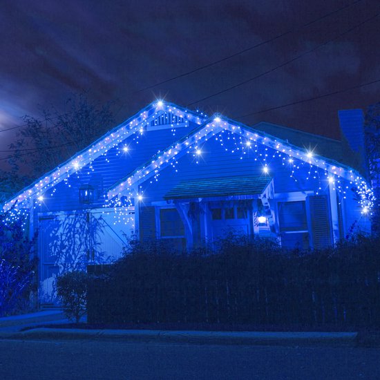 Huis verlicht met blauwe LED-ijspegelverlichting langs de dakrand tijdens een nachtelijke hemel met volle maan.