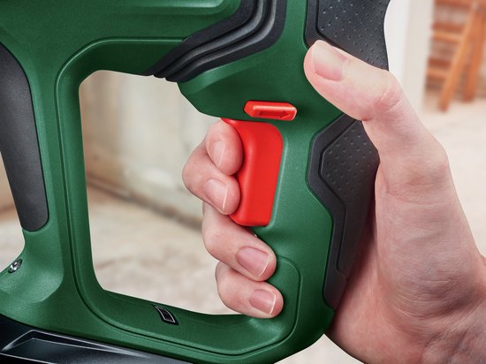 Vinger drukt op rode schakelaar van groene Bosch boorhamer.