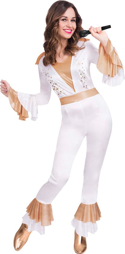 Vrouw in wit met goudkleurig disco-jumpsuit, glitterdetails, wijde mouwen en flared pijpen. Houdt microfoon vast.