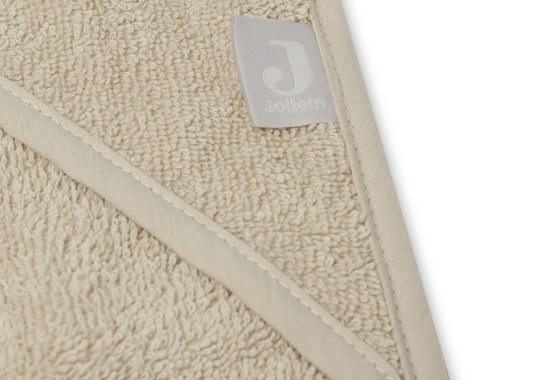 Close-up van het label 'Jollein' op een beige badcape met capuchon.