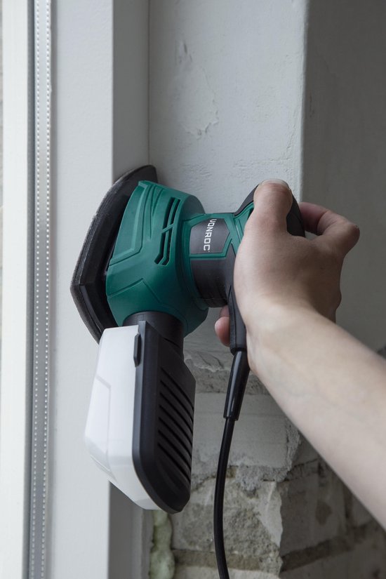 Hand met groene VONROC multislijper die een kozijn schuurt.