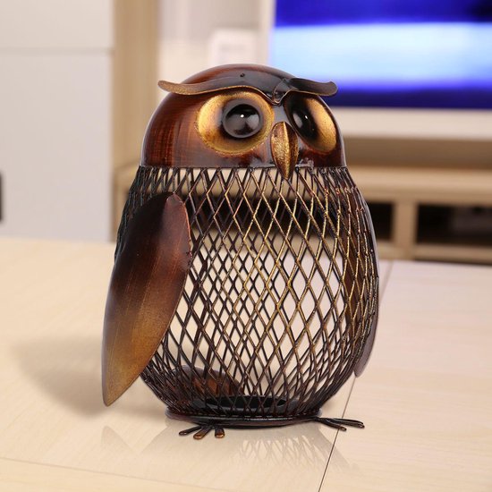 Een bruine metalen spaarpot in de vorm van een uil, op een tafel in een woonkamer.