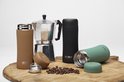 Bruine en zwarte RETULP tumblers naast een koffiezetapparaat en koffiebonen.