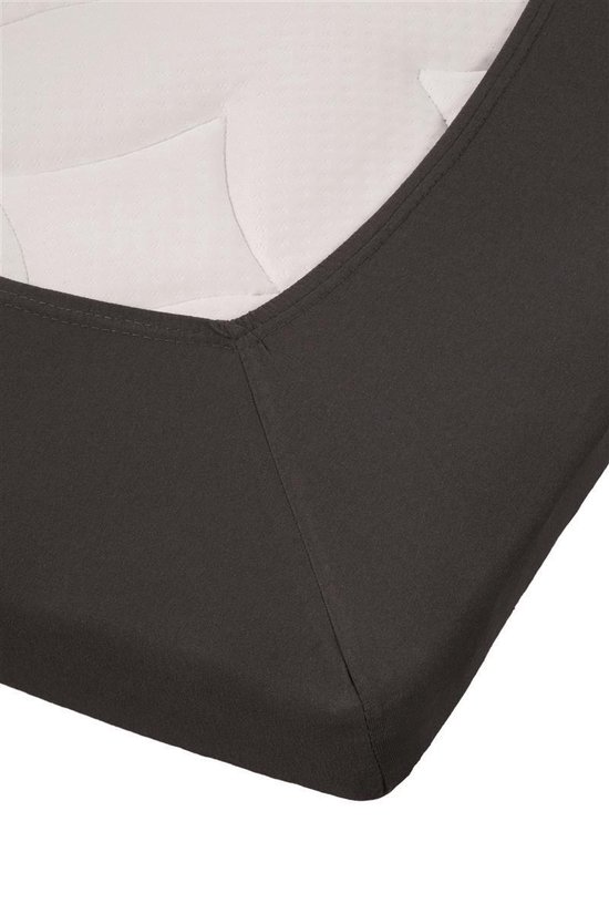 De hoek van een donkergrijs jersey topper hoeslaken op een matras met witte textuur.