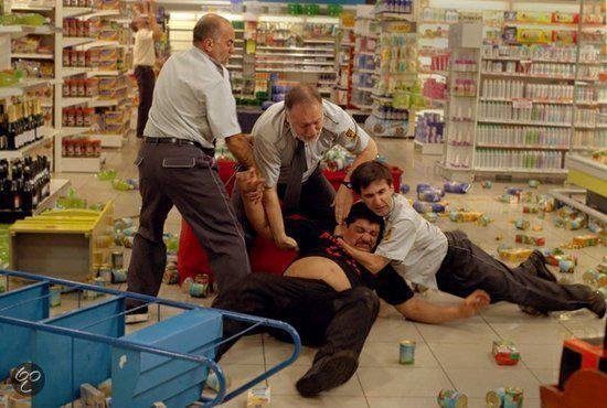 Supermarkt met gevallen producten, vijf mannen in gevecht.