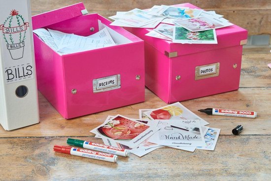 Twee roze opbergdozen, één met 'RECEPIIS', de ander met 'PHOTOS', omringd door foto's en pennen.