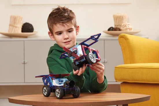 Kind bouwt met Magformers aan een magnetisch voertuig en vliegtuig aan een houten tafel.
