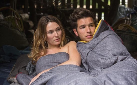 Man en vrouw liggen samen in slaapzakken, buiten.