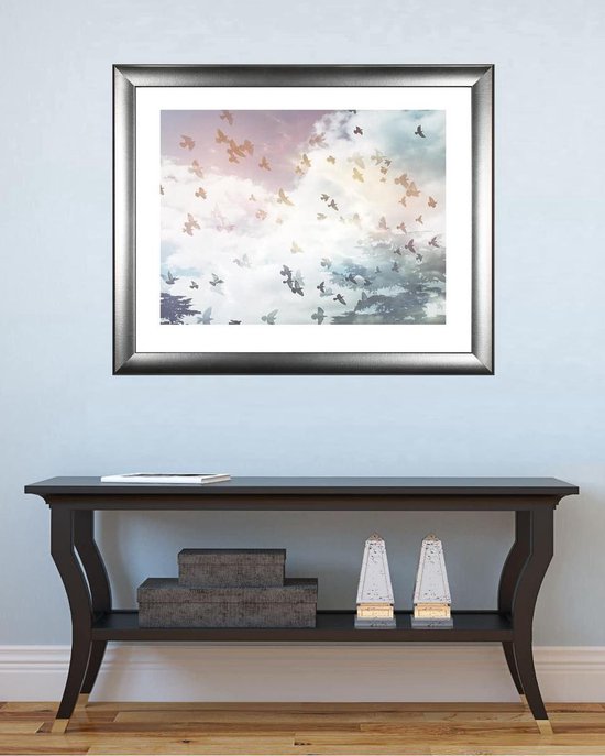 Cadre photo argenté avec une image d'oiseaux en vol, accroché au mur au-dessus d'une console.
