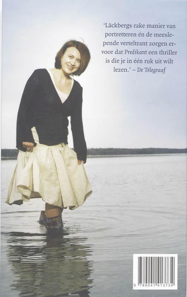 Een vrouw met bruin haar staat in het water, gekleed in een witte rok en een donker vest. Achtergrond is een meer.
