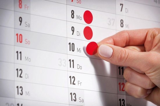 Vinger plaatst een rode sticker op de kalender bij datum 10.