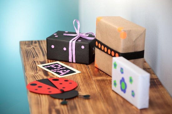 Twee ingepakte cadeaus, één zwart met roze stippen en één bruin met oranje stippen.