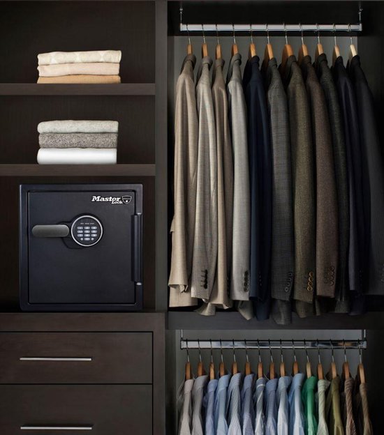 Zwarte Master Lock kluis met digitaal cijferslot in een inbouwkast naast kleding.