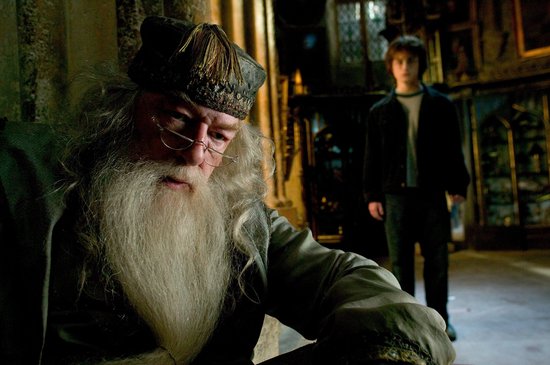 Albus Perkamentus met lange grijze baard en bril, Harry Potter staat op de achtergrond.