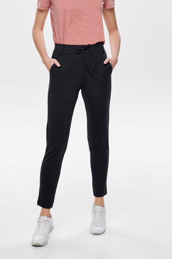 Model in zwarte Only chino broek met ceintuur en steekzakken, gedragen met witte sneakers.