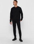 Een man met een zwarte trui en zwarte broek, staand op zwarte laarzen.