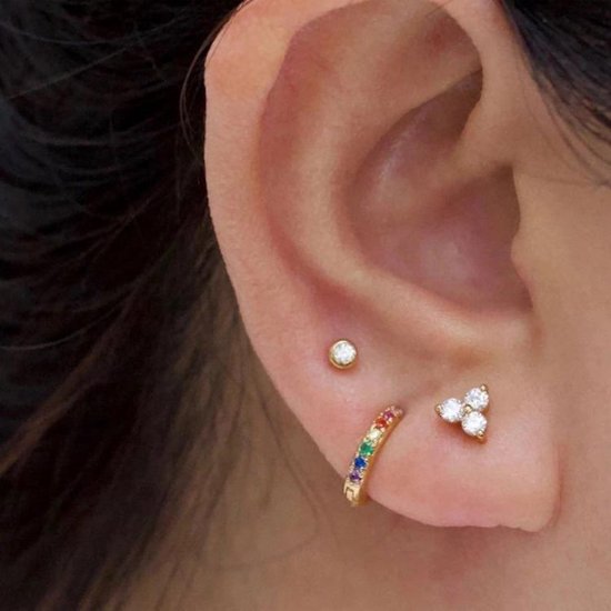 Gouden oorbel met regenboogkleurige zirkonia's en een oorsteker met drie witte zirkonia's.