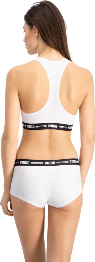 Model van achteren in wit Puma sportbh topje en bijpassende short, beide met zwarte Puma band.