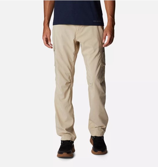 Man met een donkerblauw t-shirt en een beige cargobroek, de broek heeft zijzakken en is gedragen met zwarte sneakers.