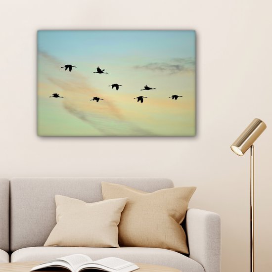 Tableau sur toile Un ciel bleu-jaune avec huit grues - 90x60 cm - Décoration murale
