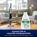 De BISSELL CrossWave staat in een woonkamer naast een fles van 236 ml natuurlijk reinigingsmiddel.