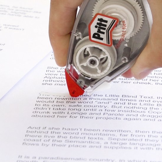 Main tenant un rouleau correcteur Pritt mini, l'appliquant sur du texte dans un document. Le rouleau est transparent avec des détails rouges.