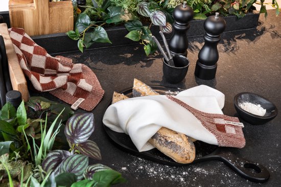 Keukendoek met roodbruine en crèmekleurige ruiten op een donkere aanrecht.