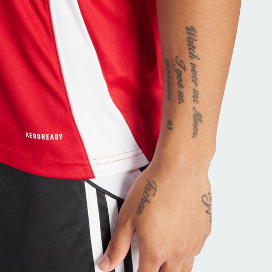 Rood sportshirt met witte accenten aan de zijkant en AEROREADY logo. Close-up van de arm.