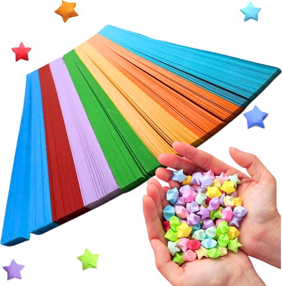 Een stapel papierstroken in regenboogkleuren wordt vastgehouden in handen, omringd door gevouwen papieren sterren.