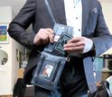 Man in pak met donkerblauwe leren tas, pakt telefoon.