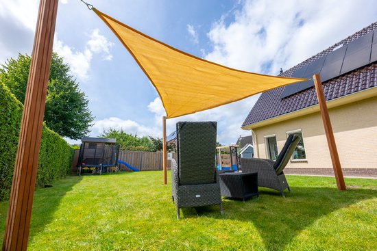 Gele driehoekige schaduwdoek boven een tuin met loungeset en trampoline.