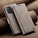 Beige PU leren telefoonhoesje met stiksels, opengewerkt om de camera te tonen. Op de achtergrond liggen bruine leren rollen.