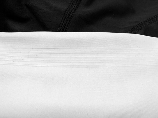 Close-up van de witte zoom met naden van een zwarte fietsbroek.