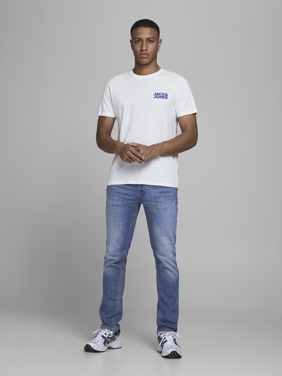 Man van voren gezien in een witte t-shirt met Jack & Jones logo en lichte spijkerbroek.