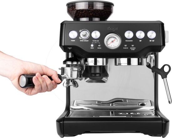 Zwarte Sage Barista Express espressomachine met een hand die de filterdrager erin plaatst.