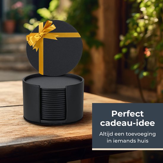 Sous-verre rond noir, emballé comme un cadeau avec un ruban jaune, dans un support noir sur une table en bois.