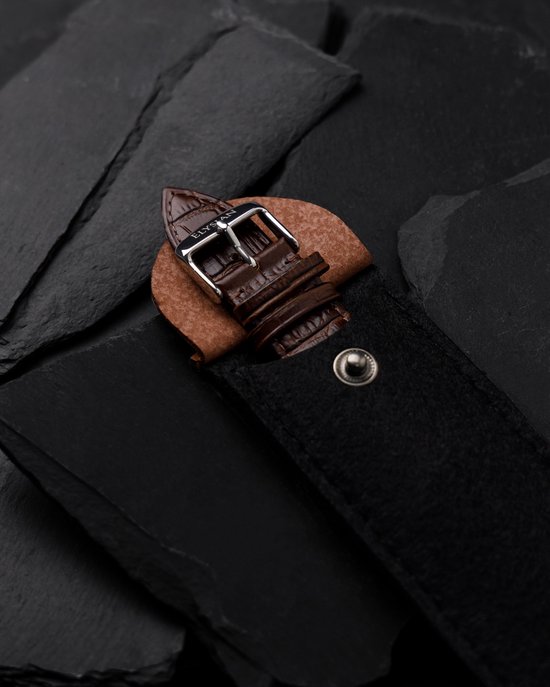 Sluiting van een bruine lederen horlogeband met krokodillenreliëf, bevestigd in een bruin leren etui.