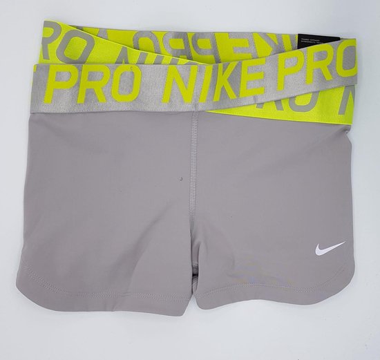 Grijze Nike Pro shorts met neongele tailleband met
"NIKE PRO"-print. Witte Nike swoosh op de linker broekspijp.
