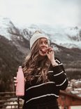 Vrouw met een roze FLASKE drinkfles in een winterse omgeving.