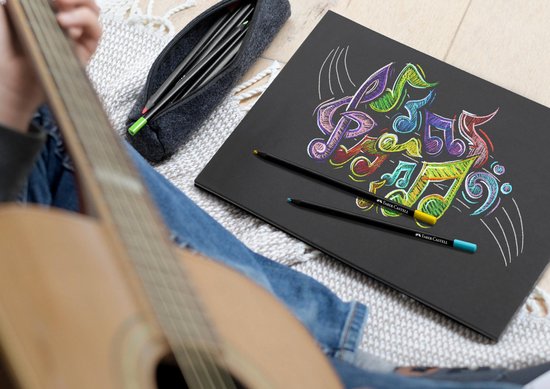 Zwart schetsboek met gekleurde muzieknoten, naast potloden en een gitaar.